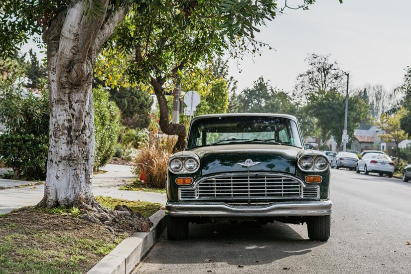 Classic car facing the camera, parked on the side of the road under a tree