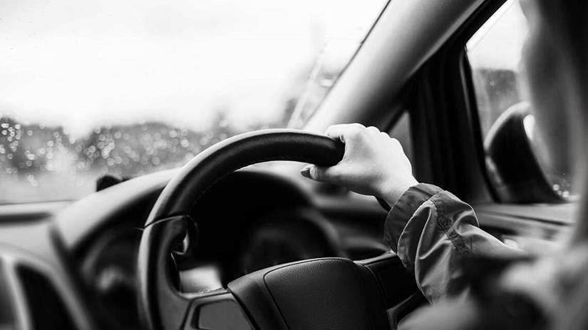 Image of steering wheel and person driving a car