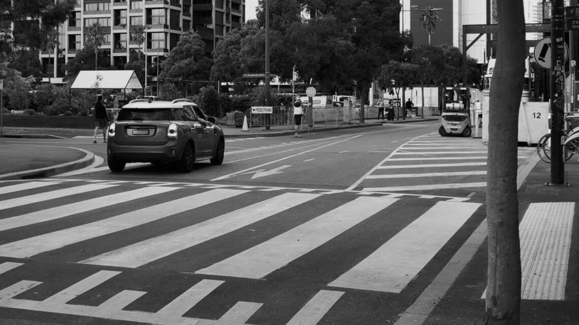 Car driving near pedestrian crossing in city street